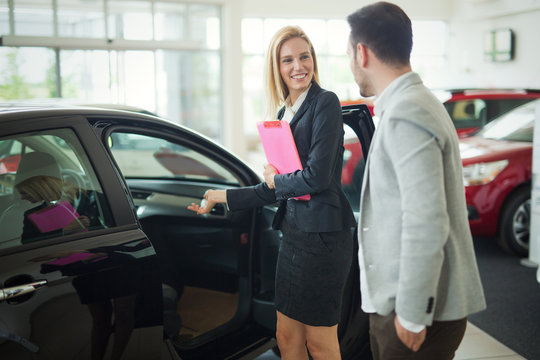 Professional salesperson during work with customer at car dealership.