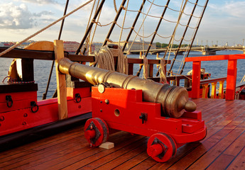 Historical cannon of an old wooden sailboat. Details deck of the ship.
