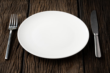 white plate fork spoon on wood background clear and without depth of field