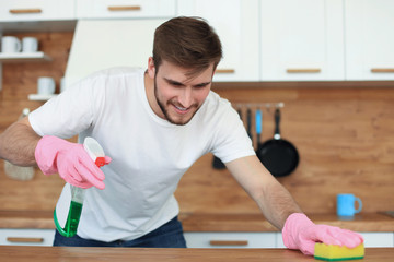 Single handsome man cleaning kitchen at home.