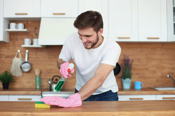 Single handsome man cleaning kitchen at home.