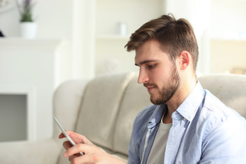 Portrait of smiling smart man using smartphone at home.