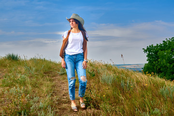 Girl in cowboy dress standing back on the top of Caucasus mountain.