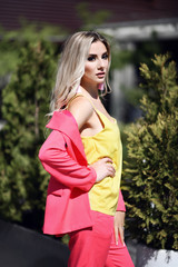 Successful young blonde woman in modern pink jacket suit and yellow blouse 