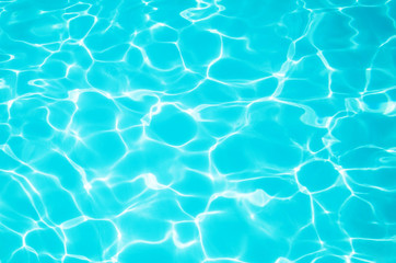 Fototapeta na wymiar Bright blue water in the pool with a sun glare. Background image, water texture. The concept of swimming in the pool, recreation. Place for text.