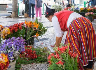 Traditionelle Blumenfrau in Tracht vor dem Markt in Funchal - obrazy, fototapety, plakaty