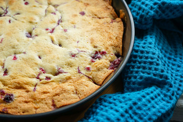 freshly baked cherry pie in a baking dish with a beautiful crafting blue towel
