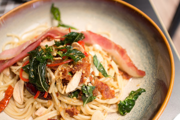 Fried bacon on hot spicy spaghetti and fried basil close up shot