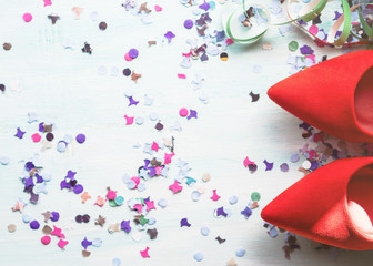 Flat lay background with woman's red pump shoes, colorful confetti, streamers. Party or sale concept.