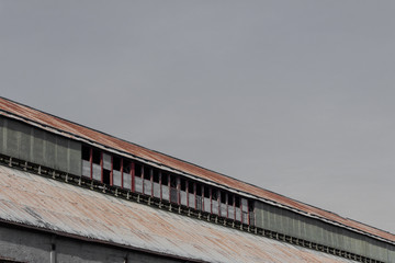 Angled view of industrial rooftop against a gray sky, corrugated metal, copy space, horizontal aspect