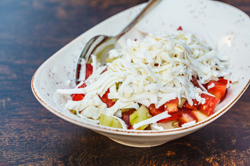 National Balkan food sopska salata in white plate on the table in the restaurant.