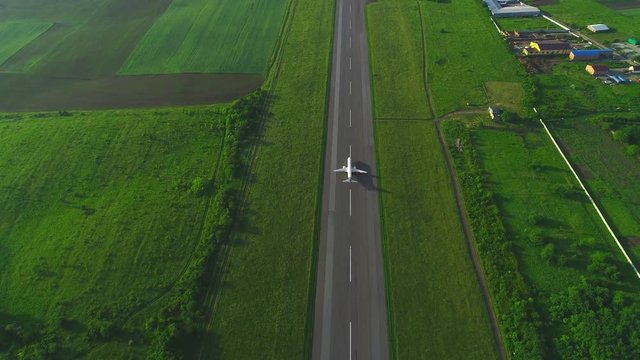 Aerial following view of white plane launching from take off runaway in the air. 4K.