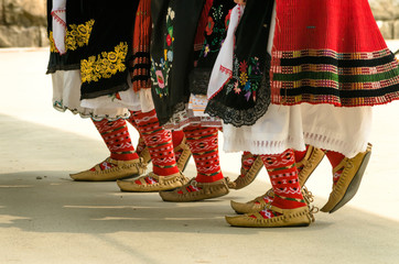 Girls dancing folk dance. People in traditional costumes dance Bulgarian folk dances. Close-up of female legs with traditional shoes, socks and costumes for folk dances.