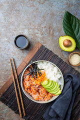 Hawaiian salmon poke bowl with seaweed, avocado, carrot, sesame seeds and rice. Top view, overhead, flat lay