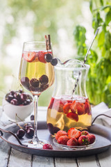 White wine sangria or punch with berries and ice in glass and pincher. Homemade refreshing fruit sangria.