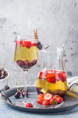 White wine sangria or punch with berries and ice in glass and pincher. Homemade refreshing fruit sangria.