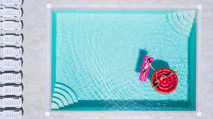 Two sexy girls in bikini are swimming in a pool on inflatable mattresses