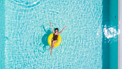 Vacation concept. Top view of slim young woman in bikini on the yellow air inflatable ring in the...