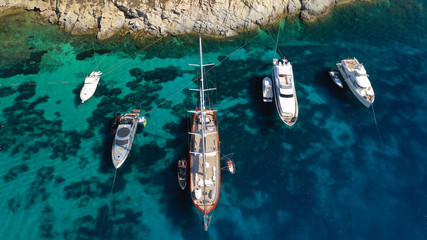 Aerial drone photo of luxury yachts docked in famous turquoise clear sea bay of Ornos, Mykonos...
