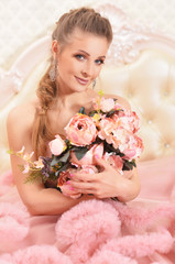 Portrait of beautiful young woman in pink dress posing in bedroom