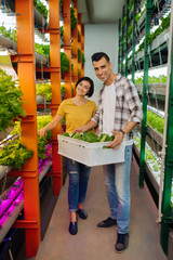 Couple of farmers smiling after growing lettuce in greenhouse