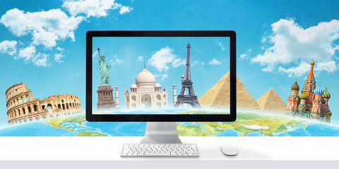 Desk with computer display and famous world tourist destinations in background. The concept of searching and planning travel through the Internet and computer.