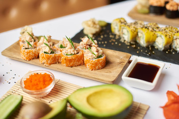 Delicious sushi roll from rice, seafood and caviar. Three course lunch ready and served for clients. On background blurred dishes of Japanese cuisine coming with wasabi and ginger.