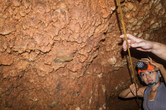  Mujer disfrutando del recorrido dentro de cuevas. Casco de seguridad naranja. Mujer feliz explorando cavernas en Tekax Yucatan. Mujer observando las formaciones rocosas dentro de la gruta de Chocante