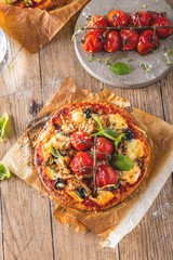 top view of delicious pizza with tomatoes on wooden table