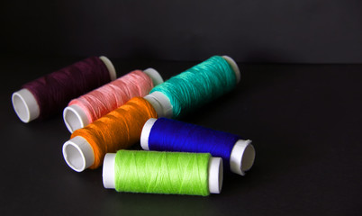 Bright colored threads for sewing on a dark background. Needlework concept and handmade. Sewing and repairing clothes