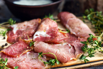 Delicious flavorful ham sliced ​​into strips on a wooden background with spices and fresh thyme. A serving of low-fat succulent farm meat pork. meat product. Food Photography