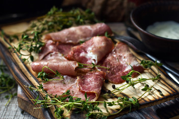 Delicious flavorful ham sliced ​​into strips on a wooden background with spices and fresh thyme. A serving of low-fat succulent farm meat pork. meat product. Food Photography