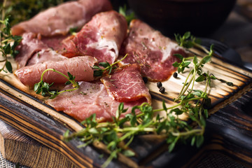 delicious pork bacon sliced ​​into strips on a wooden background with spices and fresh thyme. A serving of low-fat succulent farm meat pork. Food Photography