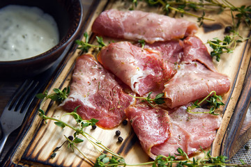 Delicious flavorful ham sliced ​​into strips on a wooden background with spices and fresh thyme. A serving of low-fat succulent farm meat pork. meat product. Food Photography