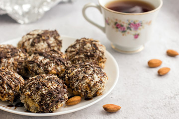 Useful homemade almond cake with coconut flakes on a light background and a cup of tea, copy space