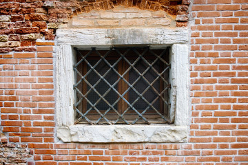 Fototapeta na wymiar Old gated window on the brick wall
