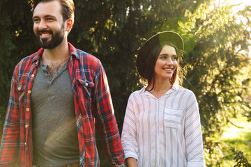 Image of young couple man and woman smiling and walking in green park