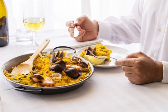 Man Eating Seafood Paella In Restaurant In Valencia, Spain. Typical Spanish Dish Lifestyle Image.