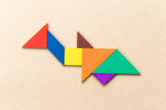 Color tangram puzzle in shark or whale shape on wood background