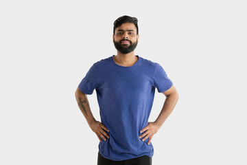 Beautiful male half-length portrait isolated on white studio background. Young emotional hindu man in blue shirt. Facial expression, human emotions, advertising concept. Standing and smiling.