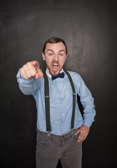 Angry screaming teacher man in eyeglasses pointing out on blackboard