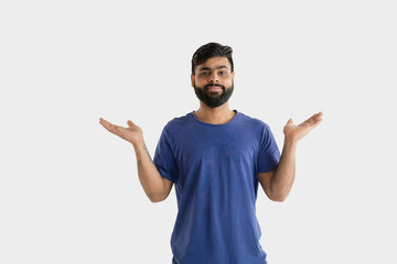 Fototapeta premium Beautiful male half-length portrait isolated on white studio background. Young emotional hindu man in blue shirt. Facial expression, human emotions, advertising concept. Showing an empty space bar.