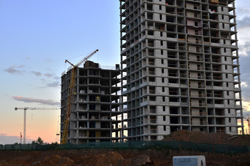 Jib construction tower crane and new residential buildings at a construction site on the sunset and blue sky background - Image