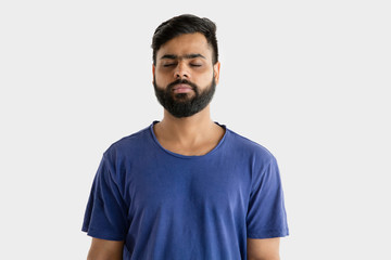 Fototapeta premium Beautiful male half-length portrait isolated on white studio background. Young emotional hindu man in blue shirt. Facial expression, human emotions, advertising concept. Standing calm with eyes closed