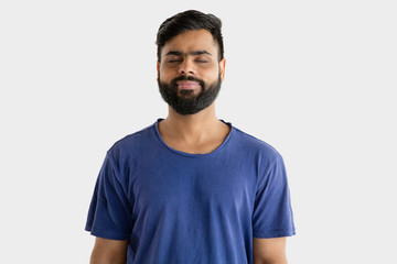 Beautiful male half-length portrait isolated on white studio background. Young emotional hindu man in blue shirt. Facial expression, human emotions, advertising concept. Standing calm with eyes closed