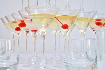 Triangular martini glasses, filled with champagne with cherries and liquid nitrogen, creating steam, shape of a pyramid
