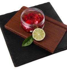 Raspberry cheesecake dessert in a jar on a black stone plate on a white background