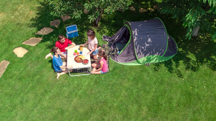 Aerial top view of family in campsite from above, parents and kids relax and have fun in park, tent...