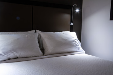 A hotel bed perfectly made and waiting for a guest needing rest.