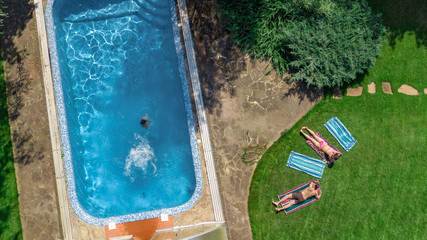 Happy family relaxing by swimming pool, aerial drone view from above of parents and kids have fun on vacation, family weekend on resort